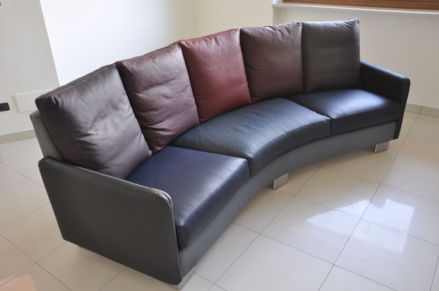 vista del divano in pelle di forma curva e cuscini con diverse tonalità di colore